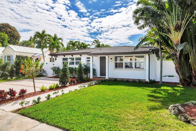 ranch-style home featuring a tile roof, fence, a front lawn, and stucco siding