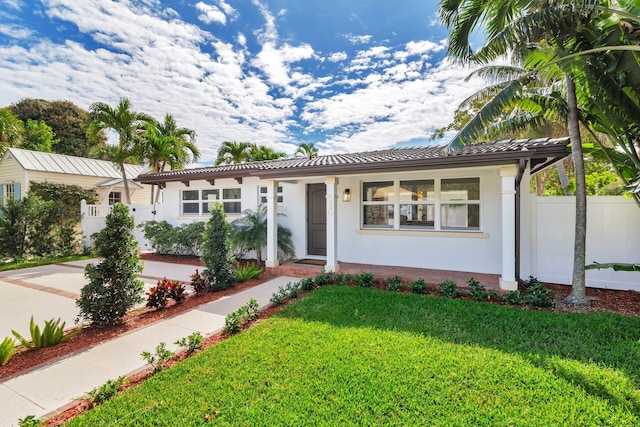 view of front of home featuring a front yard, stucco siding, a tiled roof, and fence