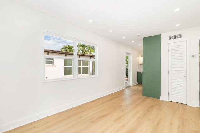 empty room featuring light wood-type flooring, baseboards, visible vents, and recessed lighting