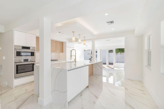 kitchen featuring visible vents, modern cabinets, a sink, a tray ceiling, and stainless steel double oven