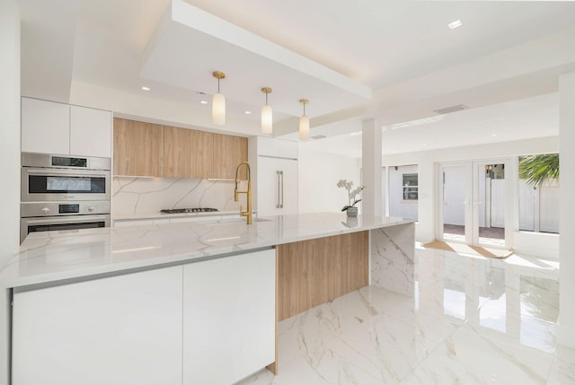 kitchen featuring white cabinets, stainless steel double oven, modern cabinets, decorative backsplash, and a sink