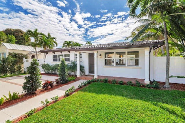 view of front of property featuring stucco siding, a tile roof, fence, and a front yard