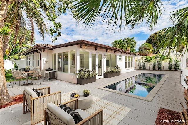 rear view of property featuring a patio, a fenced backyard, an outdoor living space, french doors, and a fenced in pool