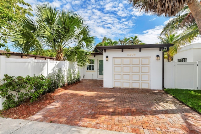 garage with decorative driveway and fence