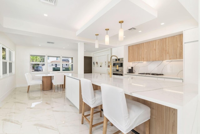 kitchen with visible vents, gas cooktop, a kitchen breakfast bar, and modern cabinets