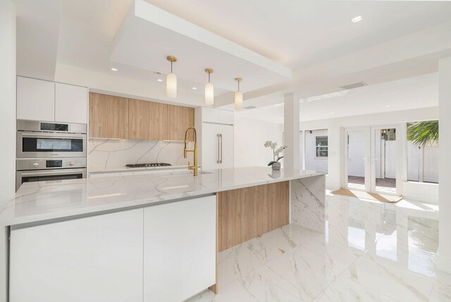 kitchen with white cabinets, light stone counters, marble finish floor, stainless steel appliances, and pendant lighting