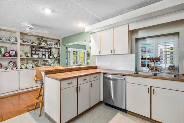 kitchen with white cabinetry, sink, kitchen peninsula, and dishwasher