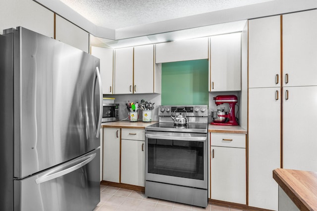 kitchen with wood counters, appliances with stainless steel finishes, a textured ceiling, and white cabinets