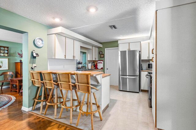 1210 Dolphin Rd, Singer Island, FL 33404 - kitchen featuring a sink, a textured ceiling, dishwasher, a peninsula, and white cabinetry