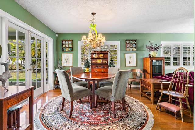 dining room with french doors, a healthy amount of sunlight, a chandelier, and wood-type flooring