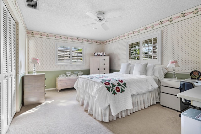 bedroom with ceiling fan, multiple windows, light carpet, and a textured ceiling