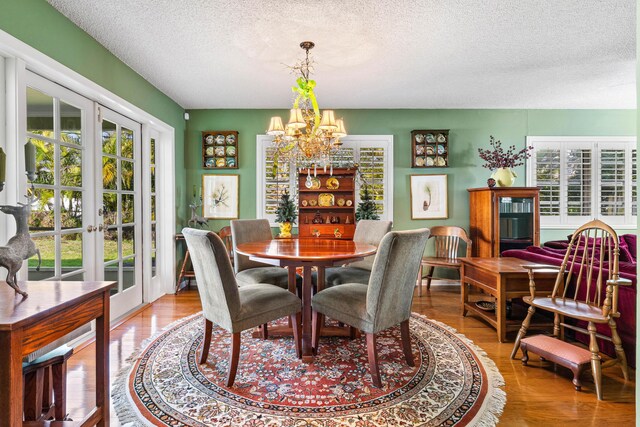1210 Dolphin Rd, Singer Island, FL 33404 - dining area with light wood finished floors, french doors, an inviting chandelier, and a textured ceiling