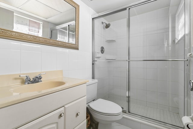 bathroom featuring vanity, tile walls, walk in shower, and toilet