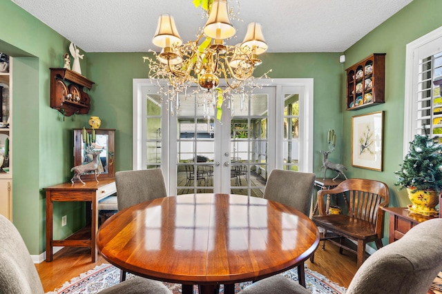 dining space featuring a notable chandelier, hardwood / wood-style flooring, french doors, and a textured ceiling