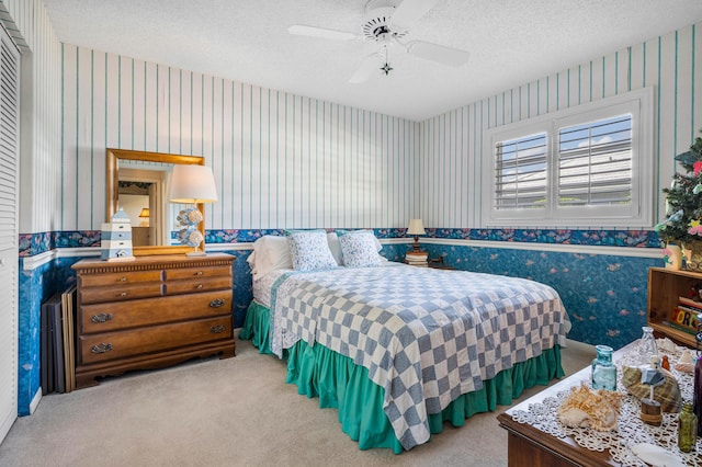 carpeted bedroom featuring ceiling fan and a textured ceiling