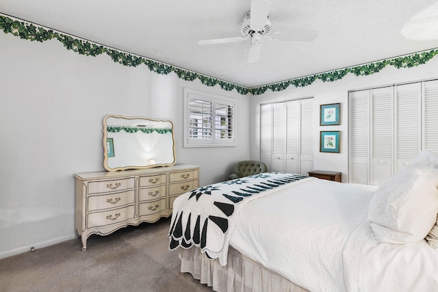 bedroom with ceiling fan, a textured ceiling, carpet, and two closets