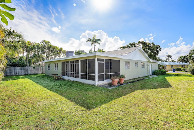 rear view of house featuring a yard and a sunroom