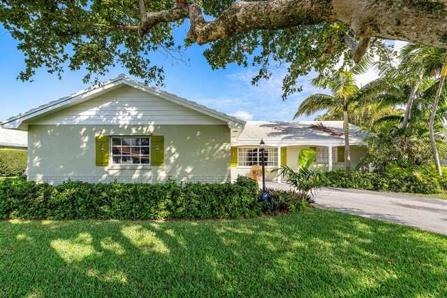 1210 Dolphin Rd, Singer Island, FL 33404 - single story home featuring a front lawn, aphalt driveway, an attached garage, fence, and stucco siding
