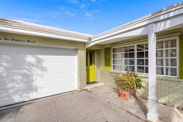 1210 Dolphin Rd, Singer Island, FL 33404 - property entrance with brick siding, aphalt driveway, and a garage