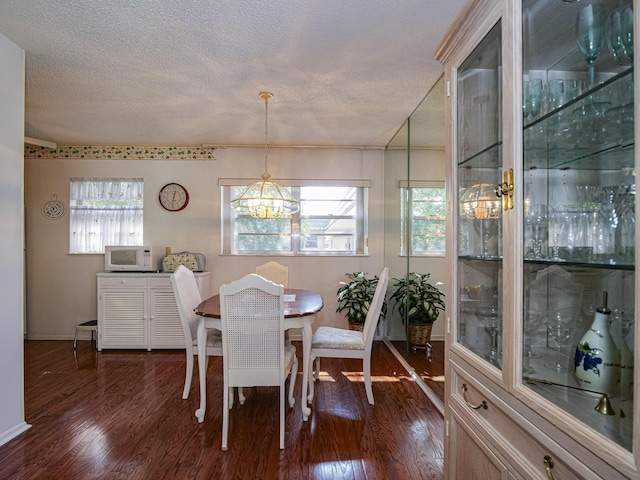 dining area with dark hardwood / wood-style flooring, a notable chandelier, and a textured ceiling