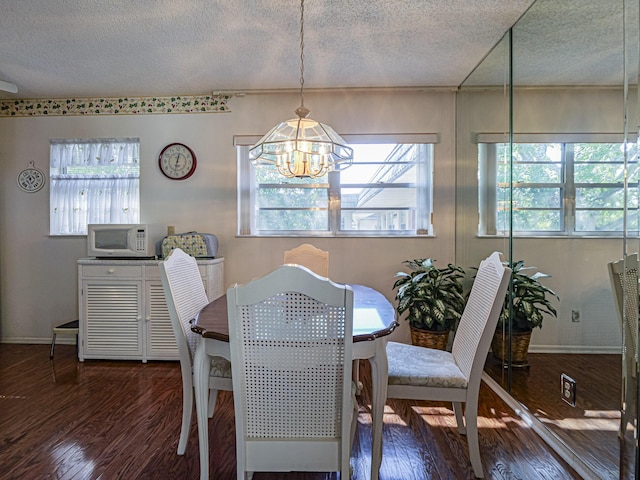 dining area with dark wood-type flooring, a textured ceiling, and a notable chandelier