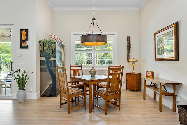 dining space with baseboards, light wood-type flooring, and crown molding