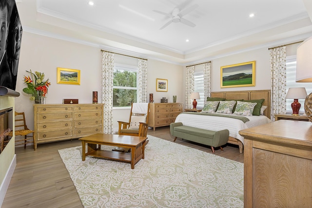 bedroom with ornamental molding, wood finished floors, a fireplace, and a raised ceiling