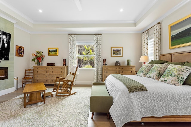 bedroom featuring ornamental molding, a fireplace, baseboards, and wood finished floors