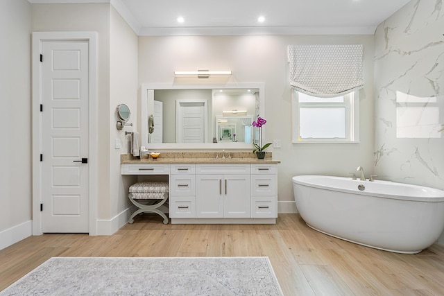 bathroom with ornamental molding, a soaking tub, vanity, and wood finished floors