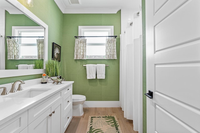 bathroom featuring a shower with shower curtain, toilet, wood finished floors, crown molding, and vanity