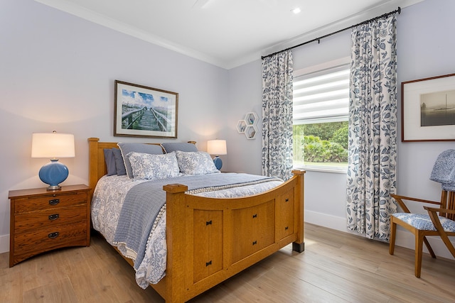 bedroom with light wood-style floors, crown molding, and baseboards