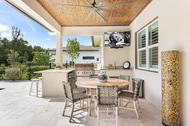 view of patio with ceiling fan, area for grilling, fence, outdoor dry bar, and outdoor dining space