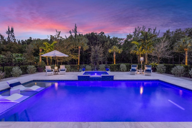 view of pool with a patio area, a pool with connected hot tub, and fence