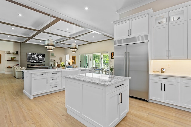 kitchen with coffered ceiling, open floor plan, a center island, built in refrigerator, and light wood-style floors