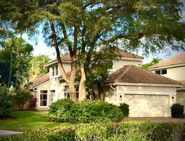 mediterranean / spanish-style house featuring a garage and a front lawn