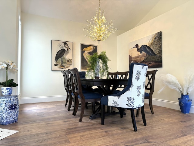 dining space with lofted ceiling, wood-type flooring, and a chandelier