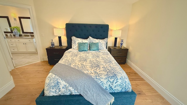 bedroom with sink, light wood-type flooring, and ensuite bath