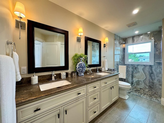 bathroom featuring tile patterned flooring, vanity, tiled shower, and toilet