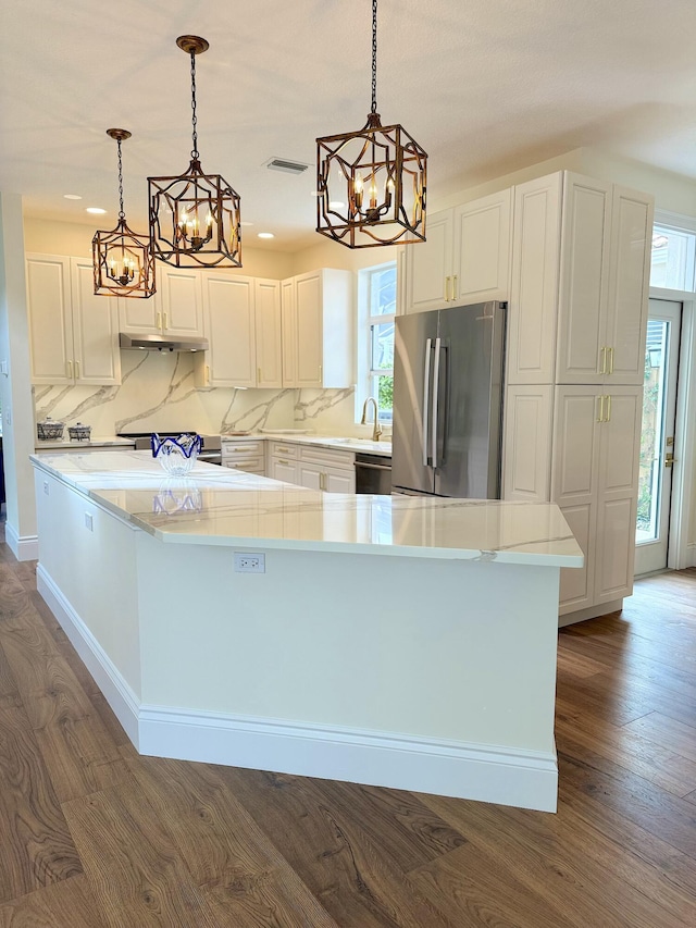 kitchen featuring stainless steel appliances, decorative light fixtures, and white cabinets