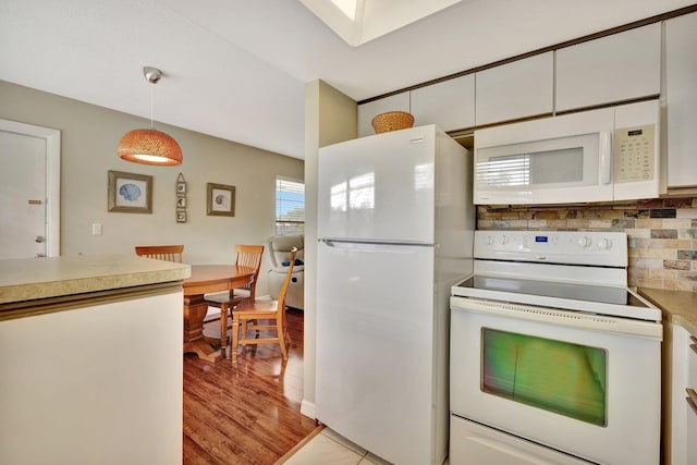 kitchen featuring pendant lighting, tasteful backsplash, white cabinets, white appliances, and light hardwood / wood-style flooring