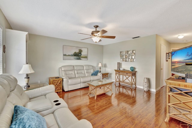 living room featuring wood-type flooring, ceiling fan, and a textured ceiling