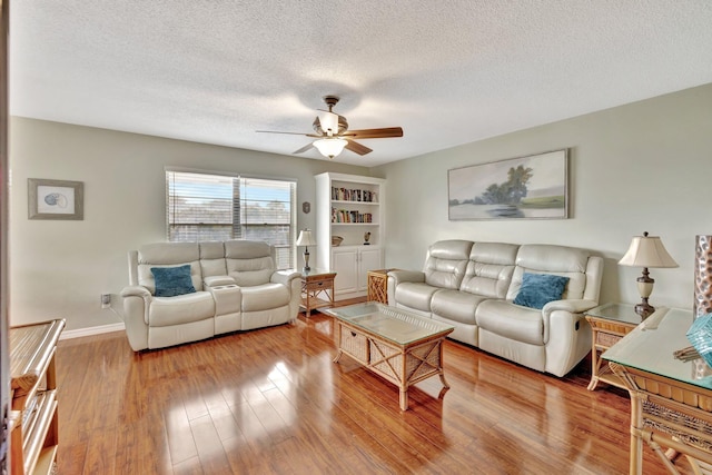 living room featuring ceiling fan, a textured ceiling, and light wood-type flooring