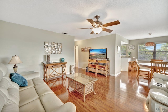 living room featuring wood-type flooring, ceiling fan, and a textured ceiling