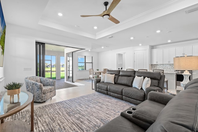 tiled living room featuring crown molding, ceiling fan, and a tray ceiling