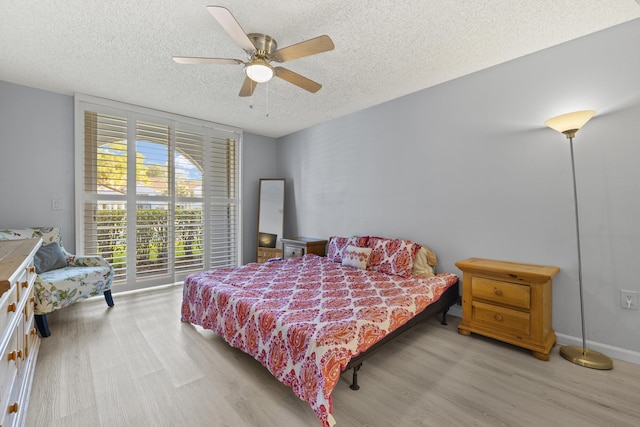 bedroom featuring ceiling fan, light hardwood / wood-style floors, and a textured ceiling