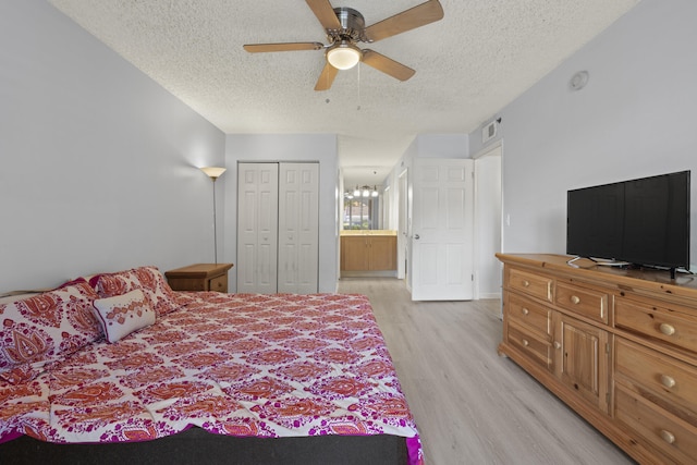 bedroom with ceiling fan, a closet, light hardwood / wood-style floors, and a textured ceiling