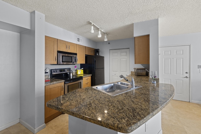 kitchen featuring appliances with stainless steel finishes, kitchen peninsula, sink, and a textured ceiling