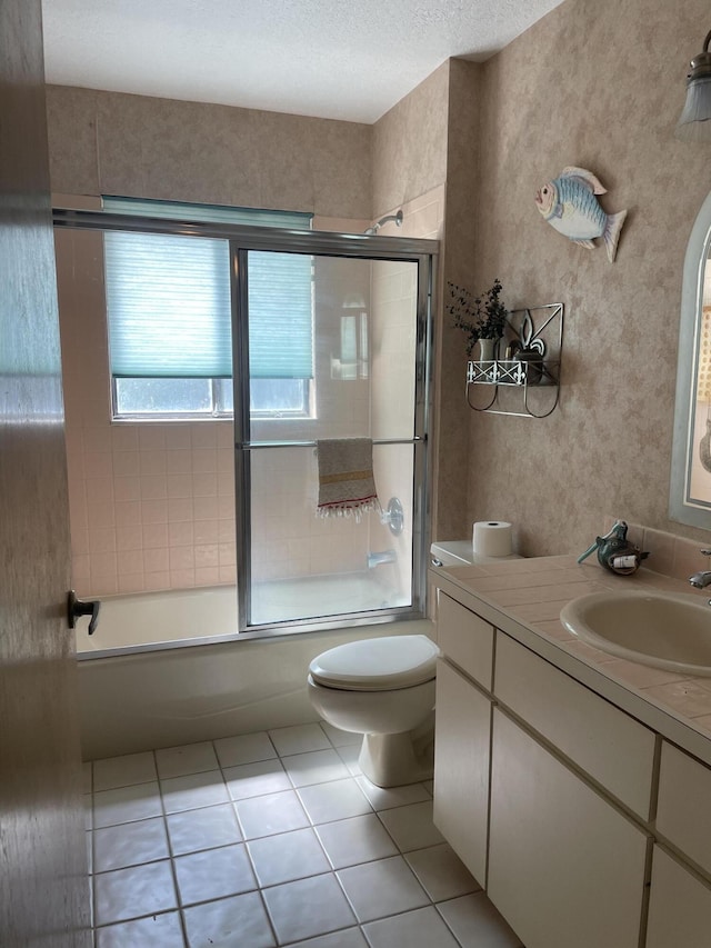 full bathroom with wallpapered walls, bath / shower combo with glass door, toilet, tile patterned floors, and vanity