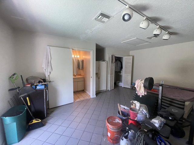 interior space featuring attic access, tile patterned flooring, visible vents, and a textured ceiling