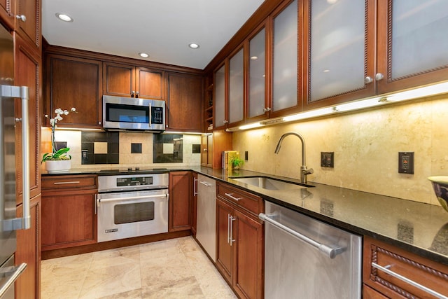 kitchen with sink, decorative backsplash, stainless steel appliances, and dark stone counters